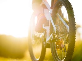 close up part of electric mountainbike sport female legs shoes summer sunny backlight rural landscape tyre